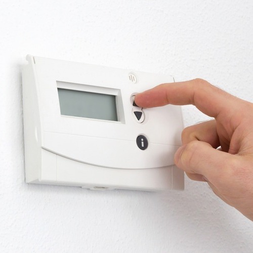 close-up of a hand adjusting a thermostat